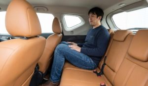 新型エクストレイルの3列目シートに大人が座ろうとして狭そうにしている様子。